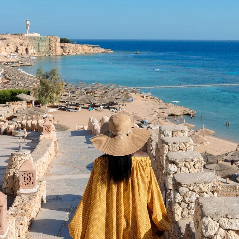 A Young Woman Wearing A Yellow Dress As She Steps Down An Old Stone Stairway In Sharm El Sheikh, Egypt, North Africa